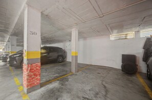 A parking garage with concrete pillars, yellow lines, and a car parked in a bay. - Apartamento 'Con Terraza' con Piscina Compartida, Wi-Fi y Aire Acondicionado (Tarifa)