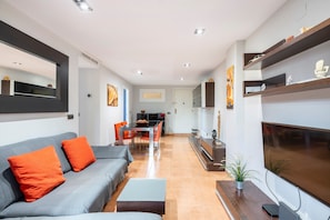 Un salon moderne comprenant un canapé, une table basse, un téléviseur et un coin repas.