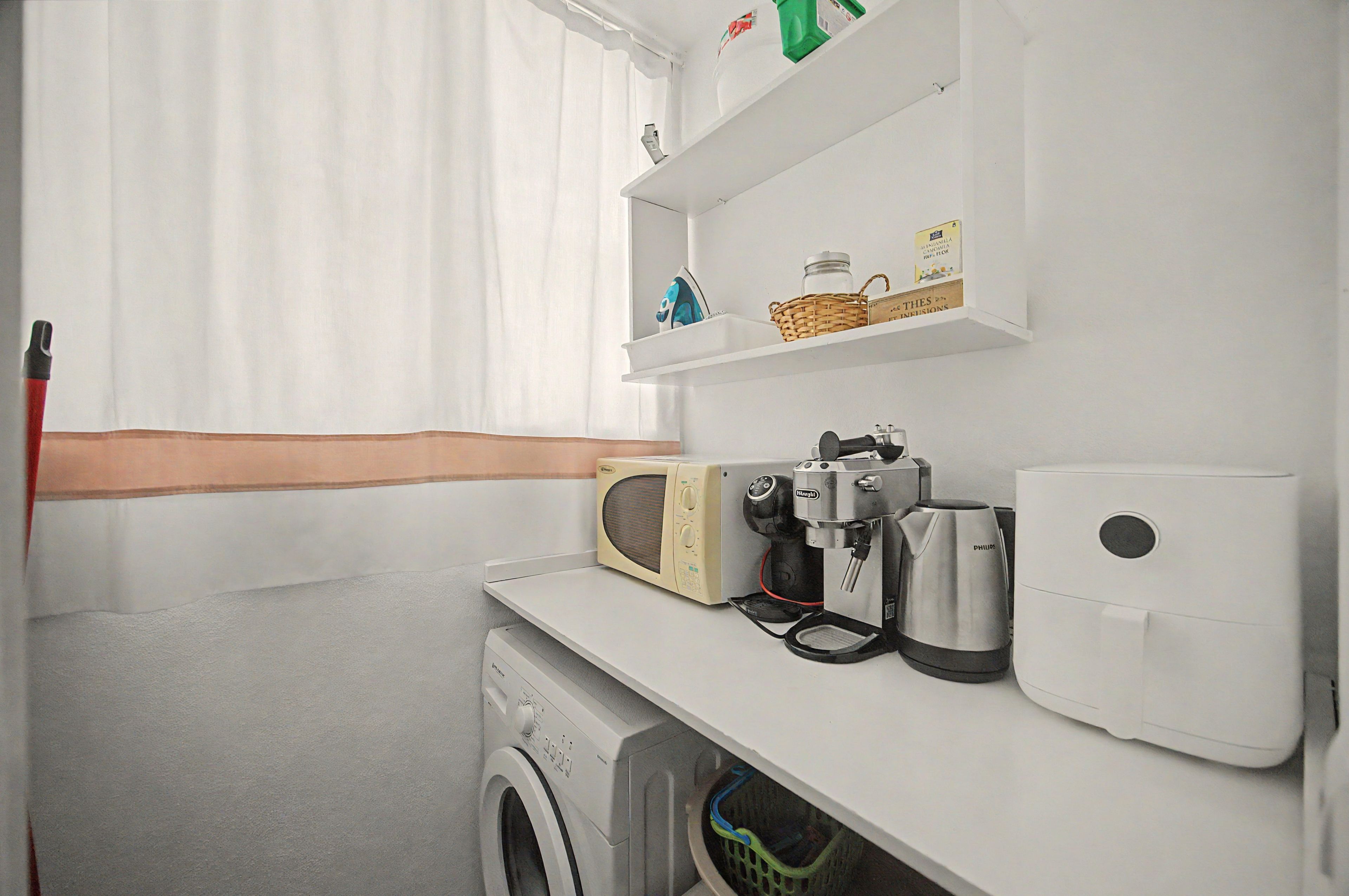 Un área de lavandería con lavadora, cafetera y dispensador de toallas de papel.