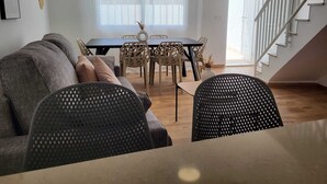 Ett modernt vardagsrum med en soffa, ett matbord, stolar och en trappa.