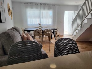 Ein modernes Wohnzimmer mit einer Couch, einem Esstisch, Stühlen und einer Treppe.