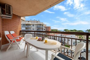 Ein Balkon mit Tisch, Stühlen und Blick auf Gebäude und Palmen.