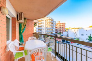 Ein Balkon mit Tisch und Stühlen, Blick auf umliegende Gebäude und eine Klimaanlage.