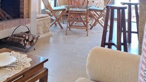Un salon avec une cheminée, un téléviseur et un coin repas comprenant des chaises et une table.