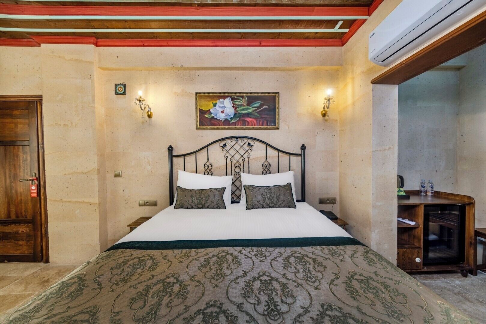 Un dormitorio con cama, un cuadro, una mesita de noche y un aire acondicionado.