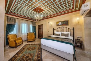 Un dormitorio con una cama grande, dos sillones, una araña y un cuadro en la pared.