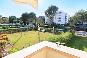 Un patio con piscina, rodeado de vegetación y un edificio blanco con balcones.
