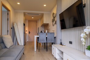 Een moderne woonkamer met een bank, televisie en een eethoek.