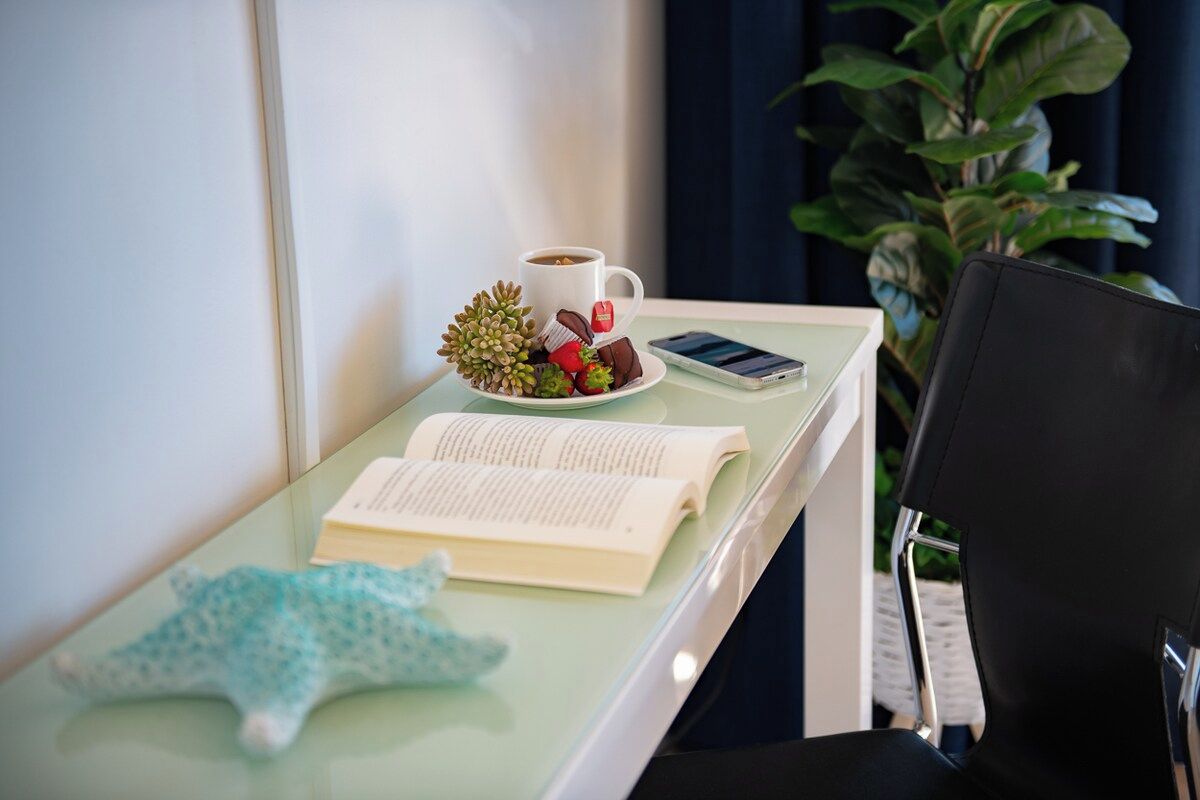 A glass table with a book, a cup of coffee, a mobile phone, and a decorative item.