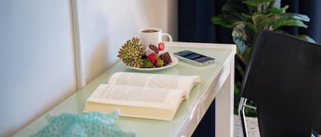 Una mesa de cristal con un libro, una taza de café, un teléfono móvil y un objeto decorativo.