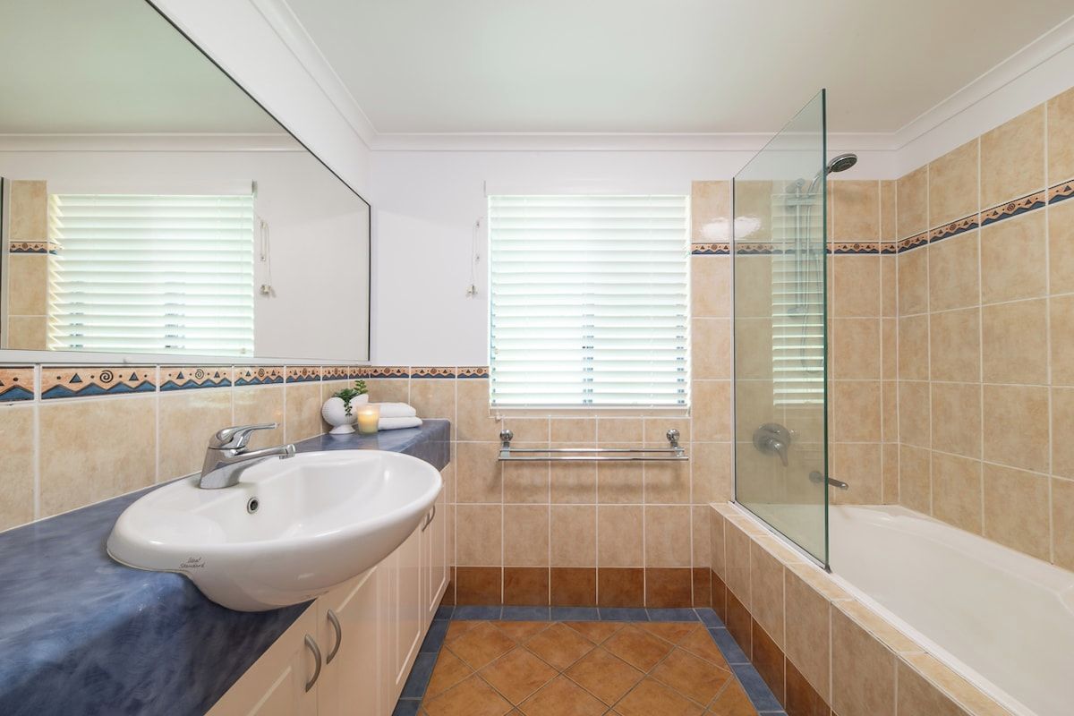 Une salle de bain avec un lavabo blanc, une douche à parois de verre et une baignoire.