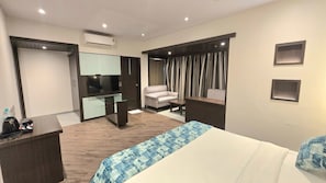 A hotel room with a bed, a desk, a chair, a television, and a mirror. - HOTEL MUMBAI HOUSE THANE (Thane, Mumbai,)