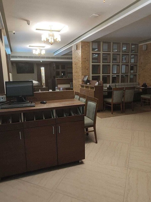 Una habitación amplia con un escritorio grande, varias sillas, una computadora y una estantería.