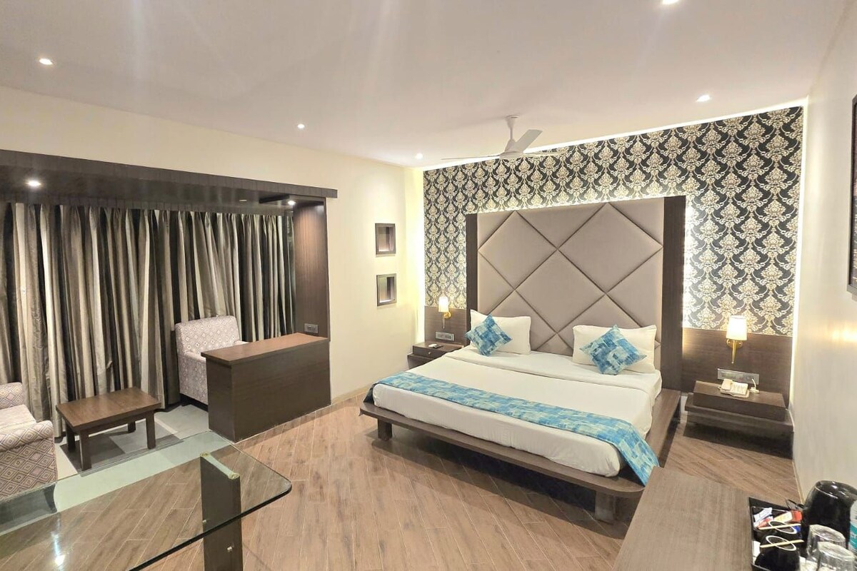 A hotel room with a bed, a sofa, a desk, and a glass table.