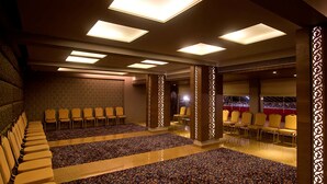 A conference room with rows of chairs, a patterned carpet, and ceiling lights.