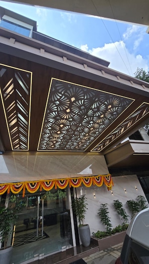 A modern building with a decorative facade, a glass entrance, and potted plants. - HOTEL MUMBAI HOUSE THANE (Thane, Mumbai,)