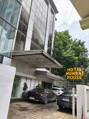 Un edificio moderno con un letrero que indica que es un hotel. Hay coches estacionados adelante.