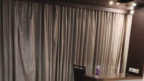 A hotel lobby with a reception desk, a chair, and a large curtain.