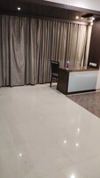 Un vestíbulo de hotel con una recepción, una silla y una cortina grande.