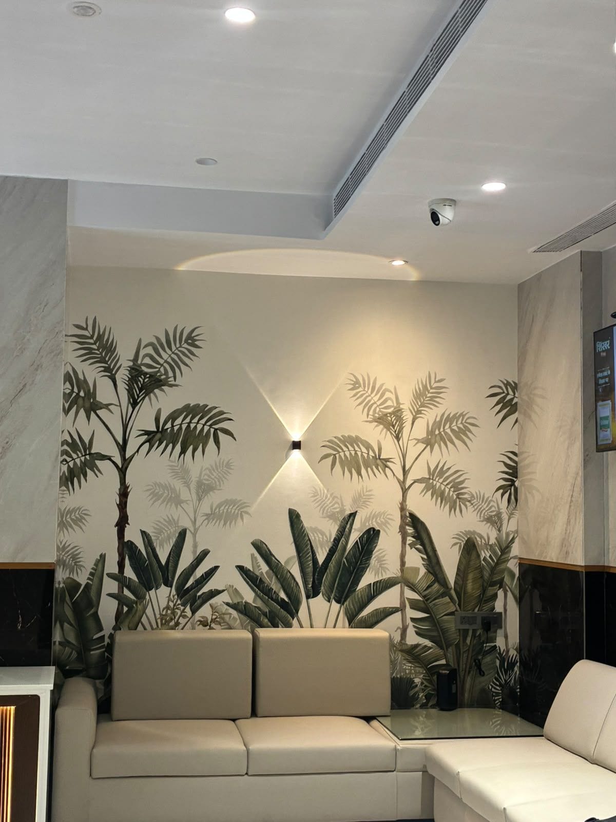 A modern interior with a sofa, a wall-mounted light fixture, and a ceiling with recessed lighting.