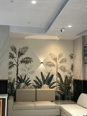 A modern interior with a sofa, a wall-mounted light fixture, and a ceiling with recessed lighting. - HOTEL MUMBAI HOUSE THANE (Thane, Mumbai,)