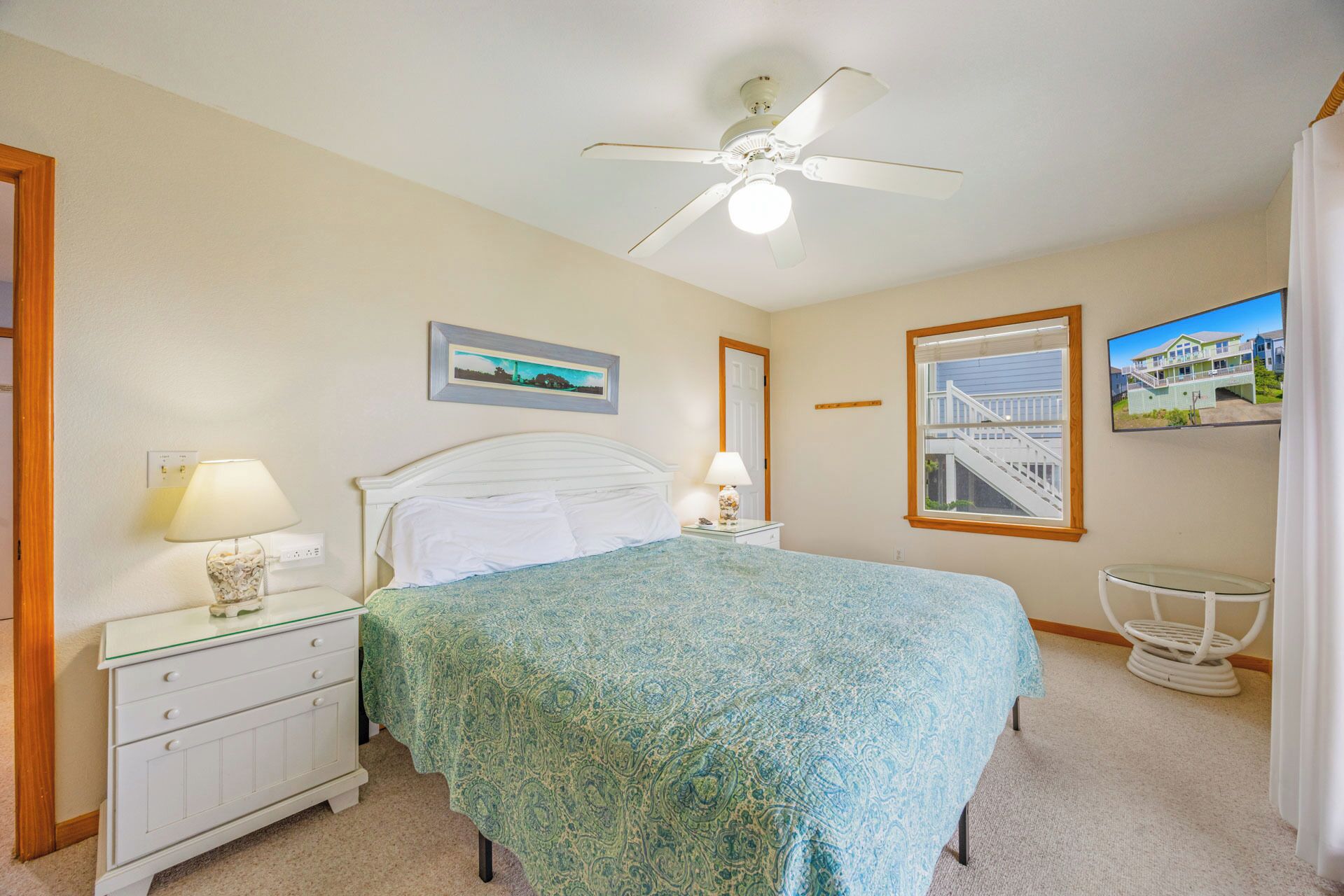 A bedroom with a bed, nightstand, lamp, ceiling fan, and two framed pictures on the wall.