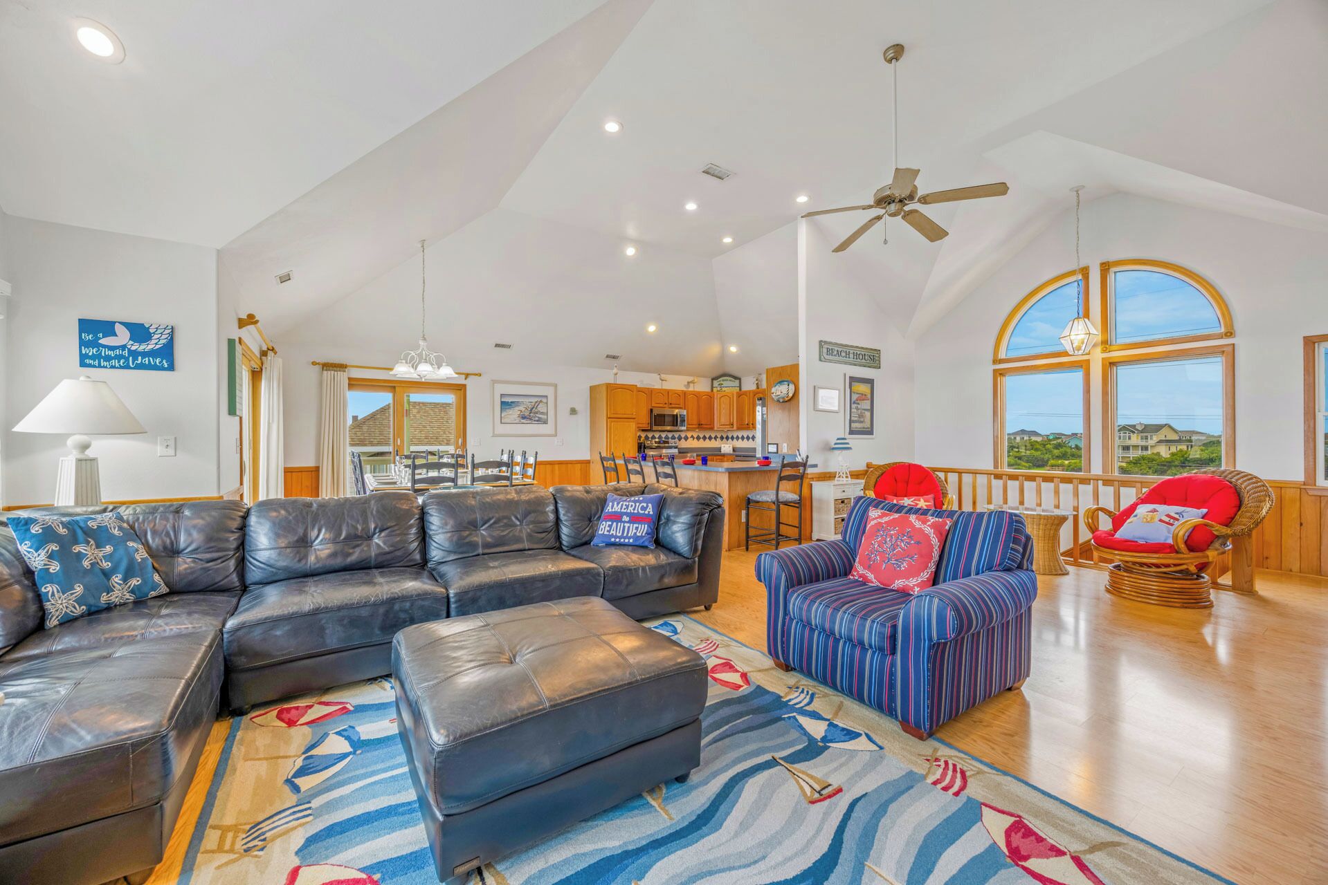 A spacious living room with a large leather sofa, a striped armchair, and a kitchen in the background.