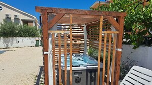 A wooden pergola with a hot tub, a white lounge chair, and a gravel patio. - Apartment Didovi Dvori 2 With Jacuzzi (Razanac)