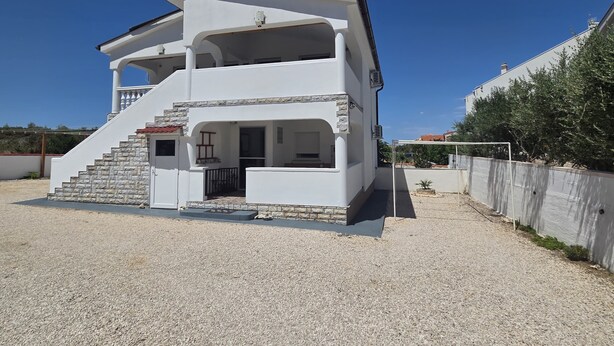 A two-story building with a balcony, a staircase, and a gravel driveway. - Apartment Didovi Dvori 2 With Jacuzzi (Razanac)