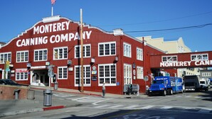 A red building with "Monterey Canning Company" signage, a flag, and parked trucks. - 4082 Sea Sights - Ocean Views from Every Room (Carmel Highlands)