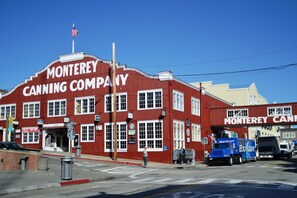 Ein rotes Gebäude mit der Beschriftung "Monterey Canning Company", einer Flagge und abgestellten Lastwagen.