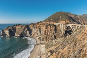Eine Küstenbrücke mit freiem Blick auf den Ozean und einer hügeligen Landschaft.