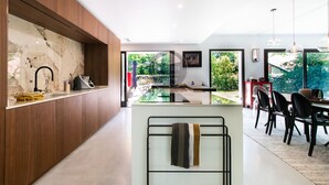 Eine moderne Küche mit Marmorarbeitsplatte, Holzvertäfelung und einem Essbereich inklusive Stühle und Tisch.