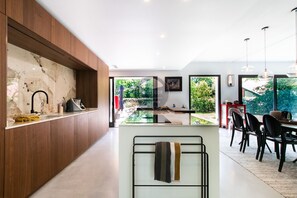 Eine moderne Küche mit Marmorarbeitsplatte, Holzvertäfelung und einem Essbereich inklusive Stühle und Tisch.
