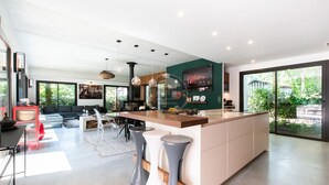 Eine moderne Küche mit Kochinsel, Barhocker und Essbereich mit einer Couch und Stühlen.