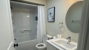 Un baño con ducha, inodoro, lavabo y espejo.
