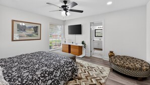 A bedroom with a bed, a desk, a TV, a ceiling fan, a window, and a door. - Central Frisco Family Getaway 3 Bedroom Home (Frisco)