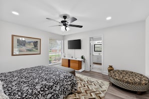 A bedroom with a bed, a desk, a TV, a ceiling fan, a window, and a door. - Central Frisco Family Getaway 3 Bedroom Home (Frisco)