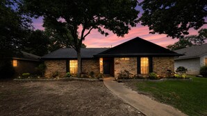 A brick house with a front entrance, a driveway, and a well-maintained lawn. - Central Frisco Family Getaway 3 Bedroom Home (Frisco)