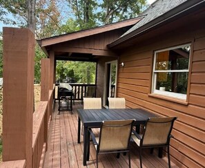 A wooden deck with a table and chairs, a covered area, and a window. - Smoky Mountain Getaway 3 Bedroom Cabin (Pigeon Forge)