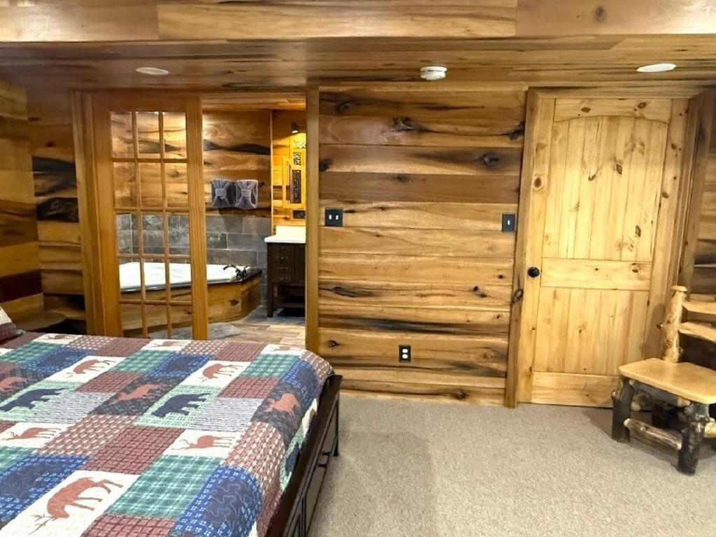 A log cabin-style room with a bed, a wooden door, and a chair.