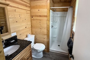 A wooden cabin bathroom with a sink, toilet, and glass shower enclosure. - Mountain Stream 4 Bedroom Chalet (Pigeon Forge)
