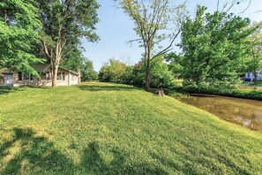 Une zone herbeuse avec une maison et un petit plan d’eau.