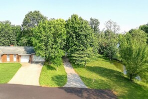 A residential property with a driveway leading to a garage, surrounded by lush greenery and trees. - Mountain Stream 4 Bedroom Chalet (Pigeon Forge)