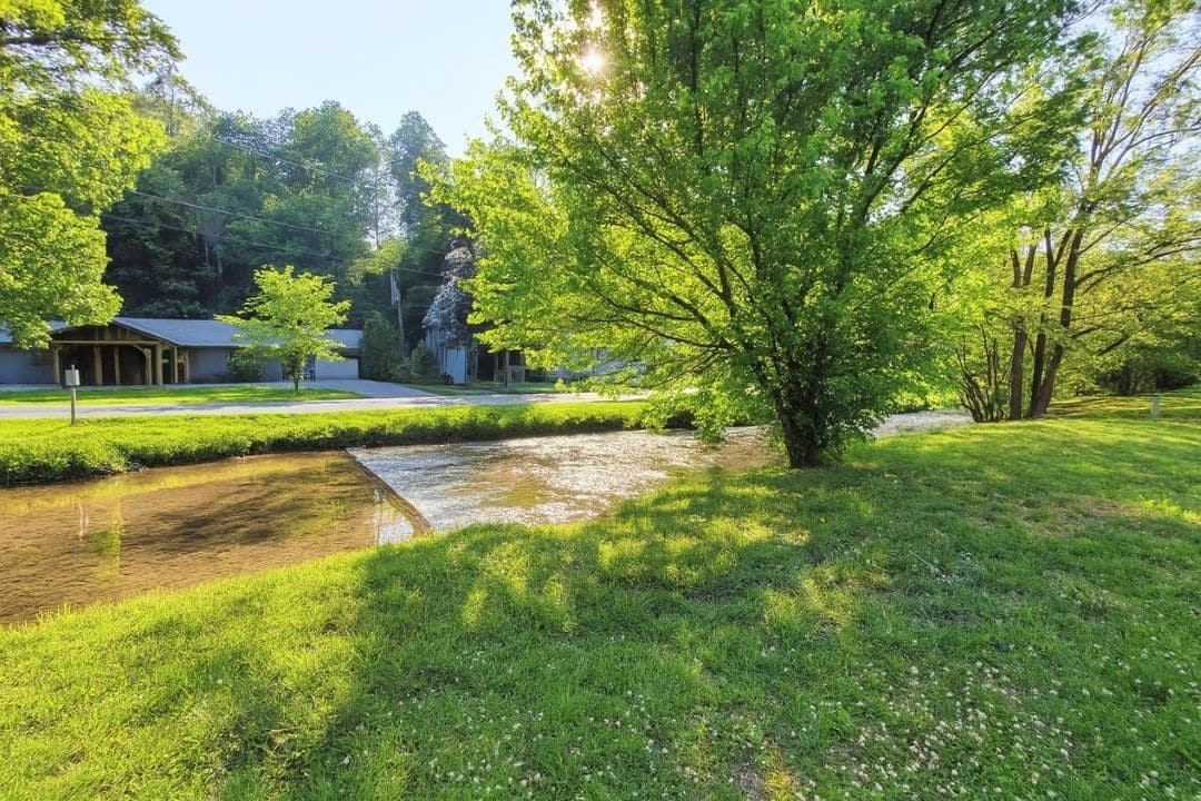 A residential area with a grassy lawn, a small water feature, and a building with a covered porch.