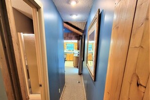 A hallway with a wooden door frame, a framed picture on the wall, and a kitchen area in the background. - Smoky Mountain Memories 2 Bedroom Cabin (Pigeon Forge)