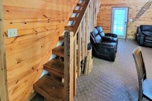 A wooden staircase leading to a living area with a sofa and two chairs. - Smoky Mountain Memories 2 Bedroom Cabin (Pigeon Forge)