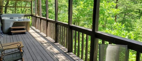 A wooden deck with a hot tub, a chair, and a table.