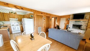 Una cocina compacta con armarios de madera, una mesa de comedor con sillas, estufa integrada y una chimenea de piedra.
