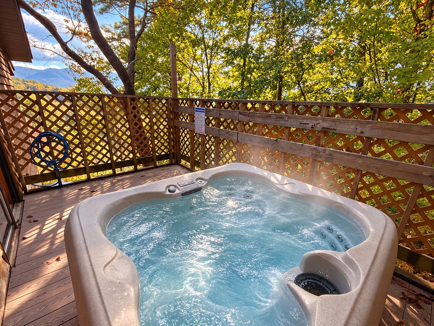 Un jacuzzi en una terraza de madera, con un cerco de madera y árboles al fondo.